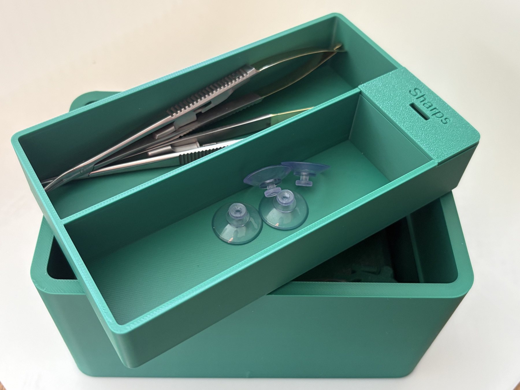 The removable integrated tool tray, with surgical instruments and suction cups, lifted above the simulator case.